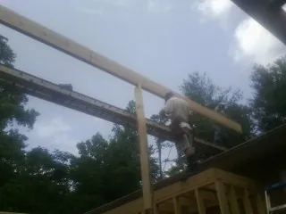 Carpenter setting a ridge beam over a new addition frame — Ice Dam Removal by Roofing Brothers in Caledonia