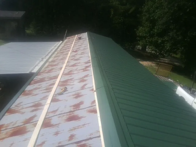 Old rusted panels beside newly installed green metal roofing — Wind Damage Roof Repair by Roofing Brothers in Caledonia
