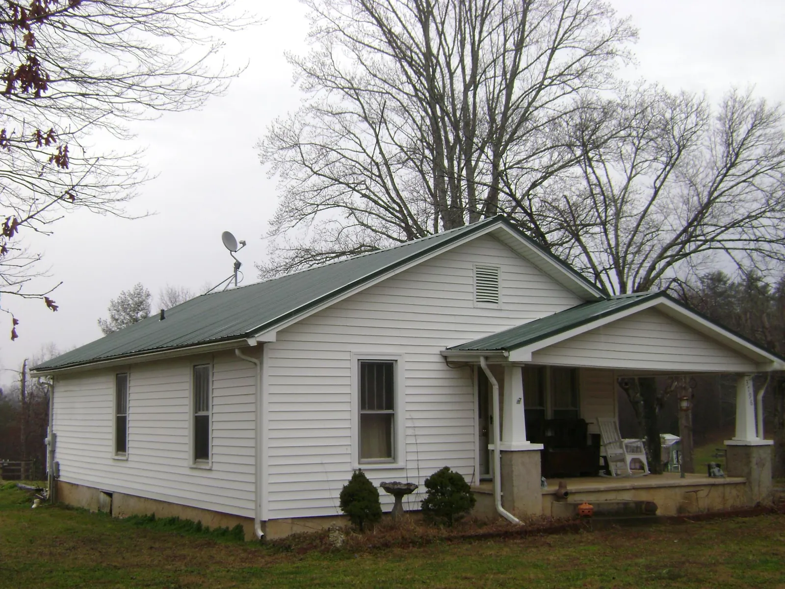 Green metal roof on a white bungalow with a side porch in Caledonia